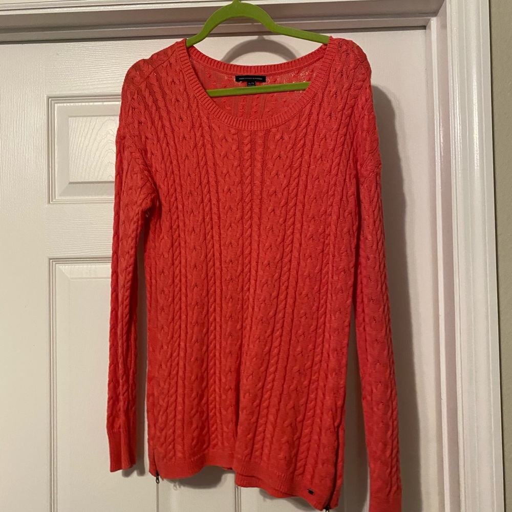Hot pink sweater with zippers on bottom corners